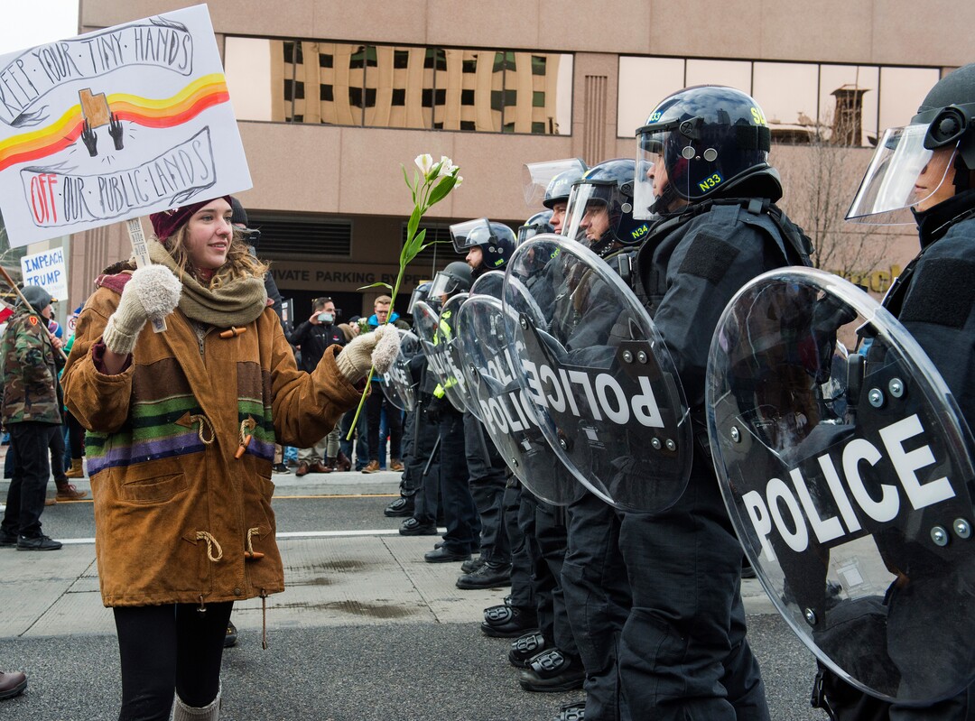 (Rick Egan  |  The Salt Lake Tribune)  Rachel Hebert of Ogden, offers flowers to the Riot Police, as protesters blocking traffic on State Street, during President Trump's visit to Salt Lake CIty, Monday, December 4, 2017.