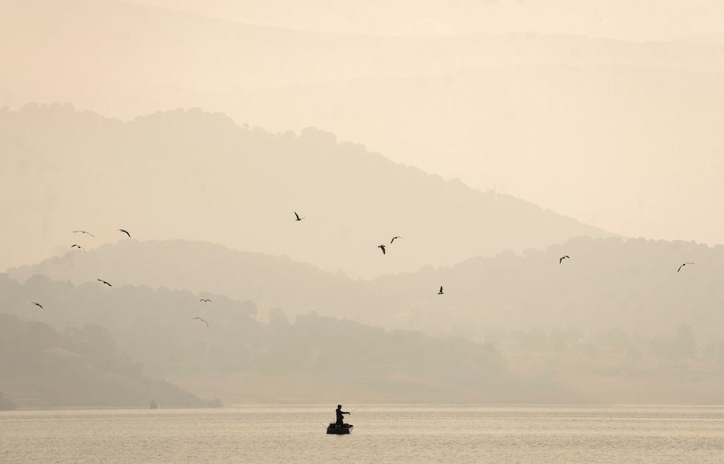 (Rick Egan | The Salt Lake Tribune)  A man fishes amid smoke from the Yellow Lake Fire at Rockport Reservoir on Wednesday, Oct. 9, 2024.