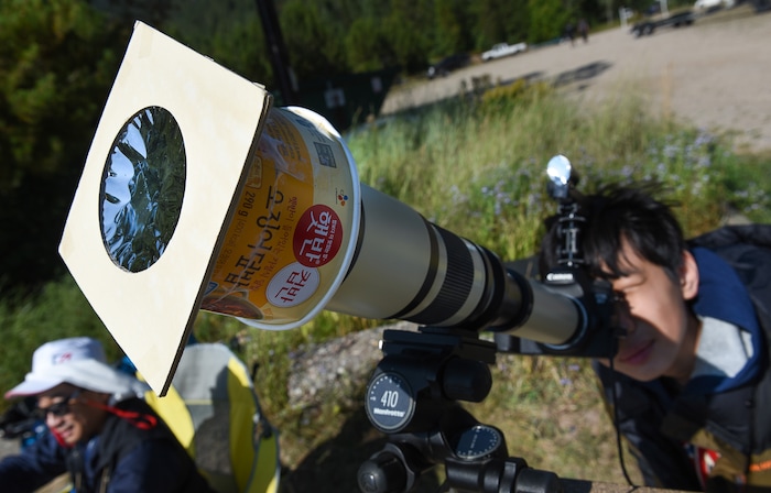 (Francisco Kjolseth  |  The Salt Lake Tribune)  An instant rice cup is used as a makeshift filter holder for Jung Sub Shim, 14, of South Korea as he watches the total eclipse of the sun from Palisades Reservoir, Idaho, on Monday, August 21, 2017.