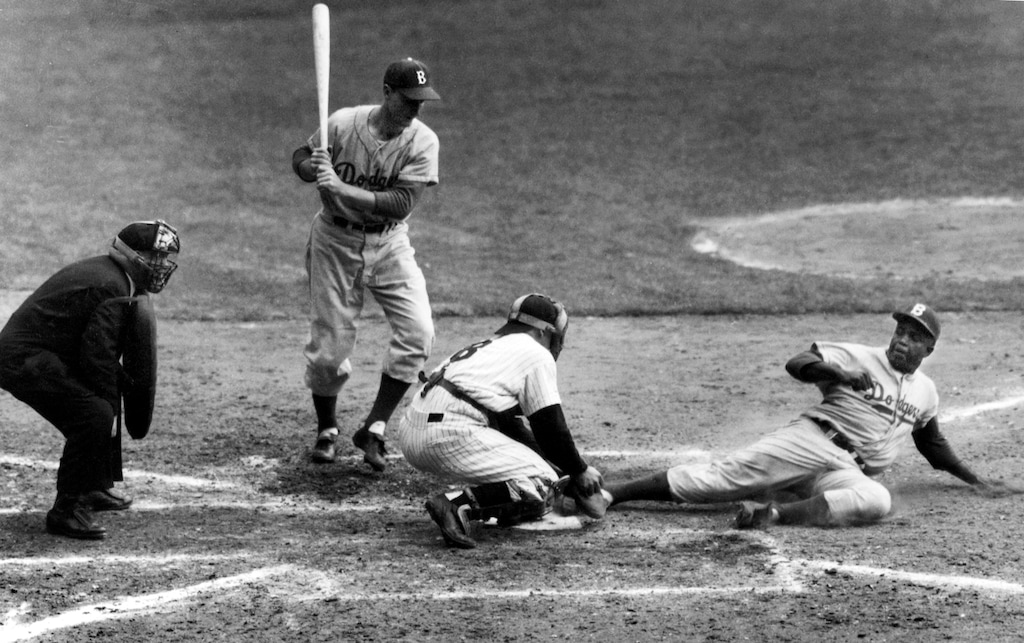 FILE - In this Sept. 28, 1955, file photo, Brooklyn Dodgers' Jackie Robinson safely steals home plate under the tag of New York Yankees catcher Yogi Berra in the eighth inning of the World Series opener at New York's Yankee Stadium.   With pinch-hitter Frank Kellert at bat, Robinson beat the throw from Yankee pitcher Whitey Ford.  Umpire is Bill Summers makes the call.  Berra, who played in more World Series games than any other major leaguer, and was a three-time American League Most Valuable Player, died Tuesday, Sept. 22, 2015, of natural causes at his home in New Jersey, according to Dave Kaplan, the director of the Yogi Berra Museum.  He was 90.  (AP Photo/John Rooney, File)