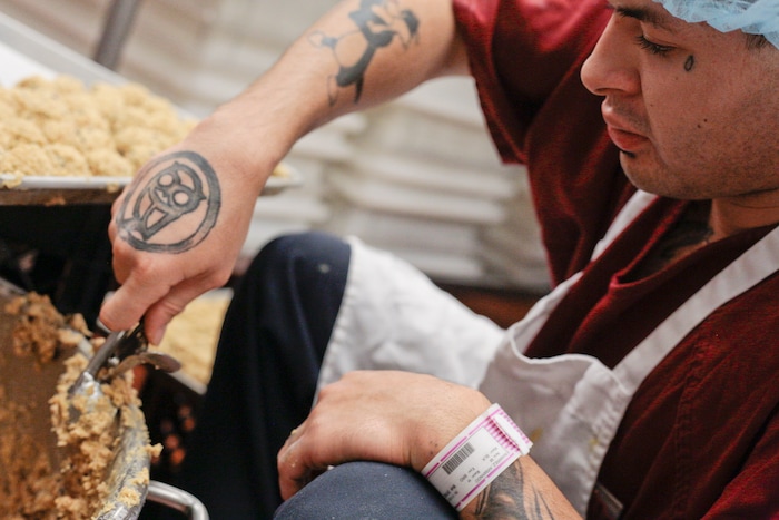 In this photo taken Jan. 23, 2018, Armando Ramirez scoops cookie dough and places it on baking sheets in the bakery area of the kitchen at the Utah County Jail in Spanish Fork, Utah. The Utah County Jail Culinary Arts program utilizes inmates labor in the commercial kitchen. (Evan Cobb/The Daily Herald via AP)