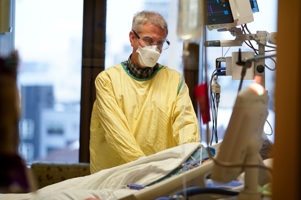 (AP Photo| Charlie Neibergall) Steve Grove, a chaplain at Hennepin County Medical Center, prays in a COVID-19 patient's room, Friday, Dec. 10, 2021, in Minneapolis. He acknowledged that he sometimes gets mad at unvaccinated patients because it "didn’t have to be this way. And now there’s a mess that perhaps was avoidable.”