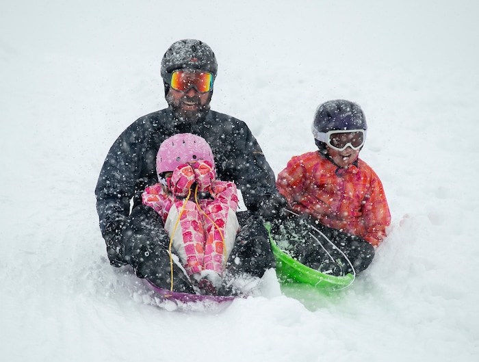 (Rick Egan  |  The Salt Lake Tribune)      
 Mark Fehlberg, sleds down the hill with his daughter Amelia 7, and son Desmond, 7 at Popperton Park, Monday, Jan. 21, 2019.


