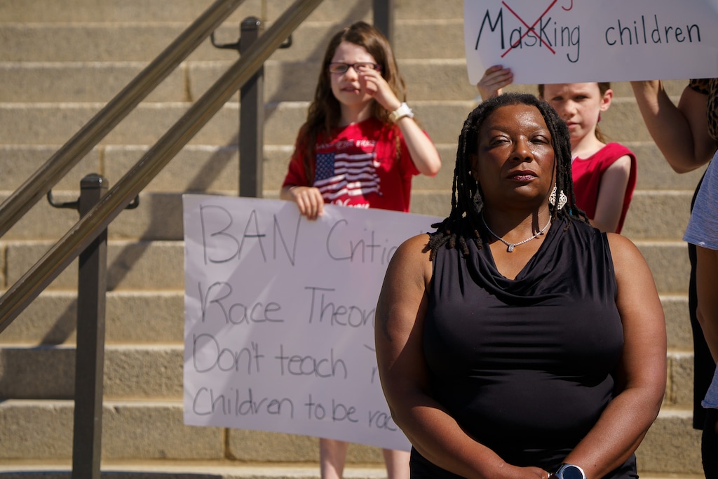 (Trent Nelson  |  The Salt Lake Tribune) Children stand behind Darlene McDonald holding opposing signs during a news conference by the Utah Educational Equity Coalition at the State Capitol in Salt Lake City on Wednesday, May 19, 2021.