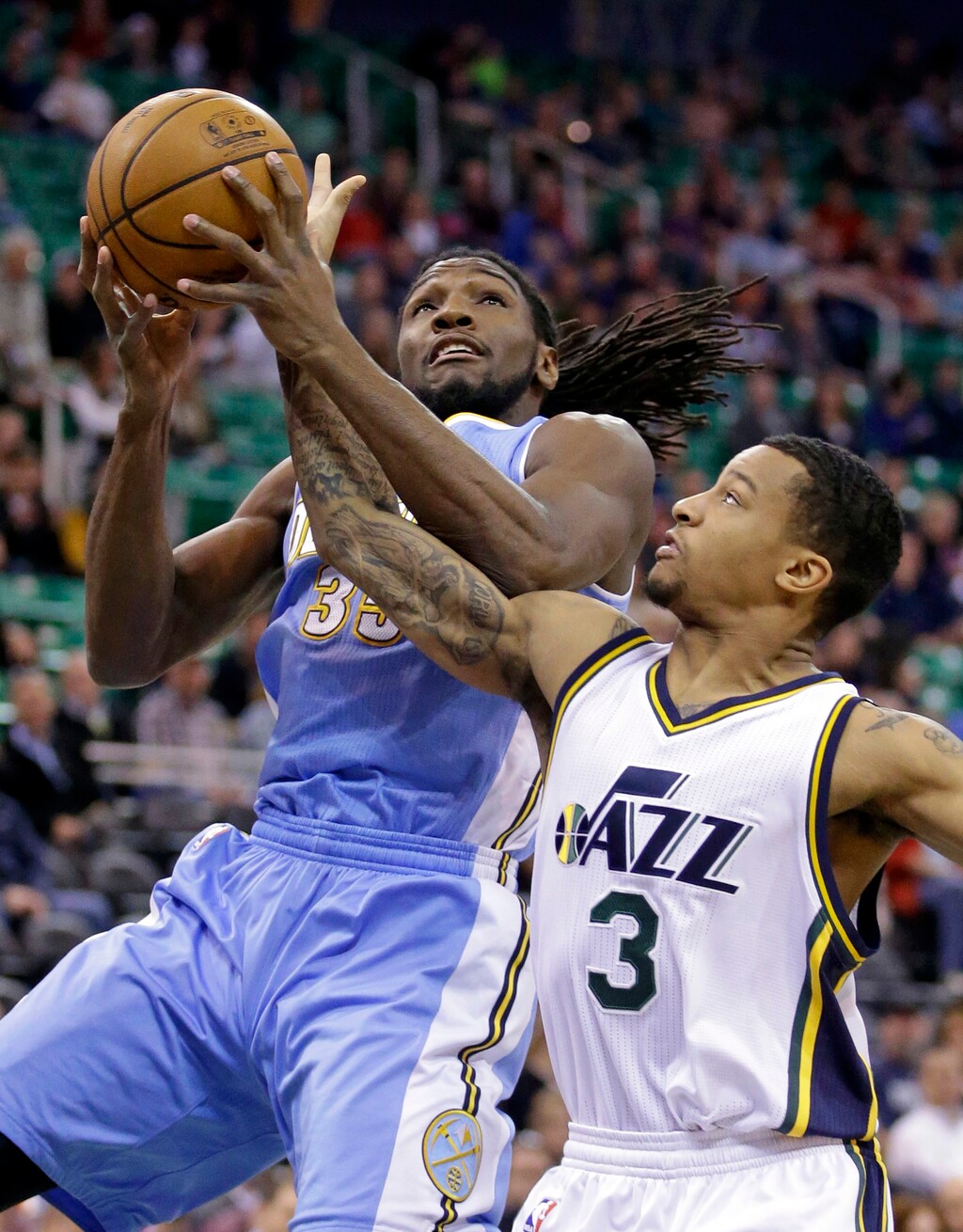 Utah Jazz's Trey Burke (3) defends against Denver Nuggets' Kenneth Faried (35) in the first half of an NBA basketball game Monday, Dec. 1, 2014, in Salt Lake City. (AP Photo/Rick Bowmer)