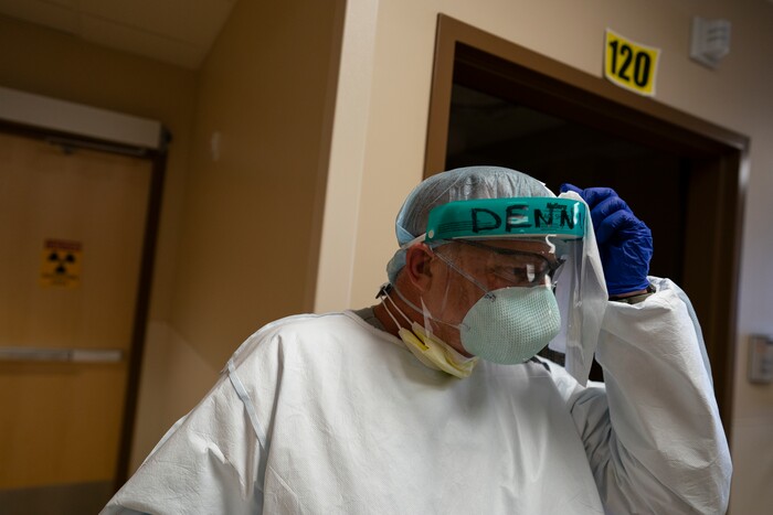 Team Rubicon volunteer Dennis Grooms, an EMT from St. Louis, cleans his face shield with a sanitary wipe after seeing a patient in the emergency room of the Kayenta Health Center on the Navajo reservation in Kayenta, Ariz., on April 23, 2020. The reservation has some of the highest rates of coronavirus in the country. Team Rubicon is helping with medical operations as cases of COVID-19 surge. (AP Photo/Carolyn Kaster)