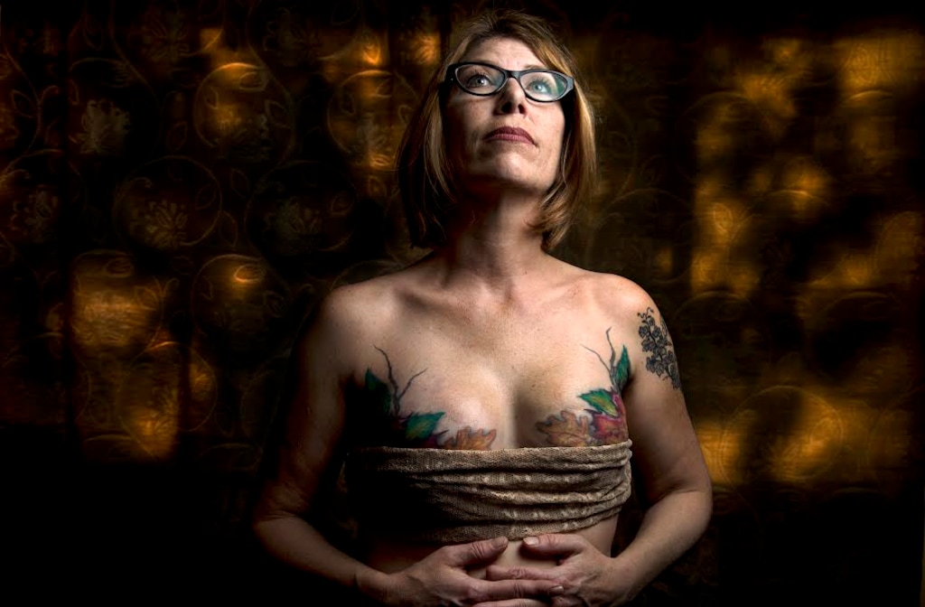 (Leah Hogsten  |  The Salt Lake Tribune) Andrea Reynolds, who had a double mastectomy in 2013, shows the artistry of Fallen Angel Tattoos founder and owner Terrina Francis, Friday, April 20, 2018 in her home. Francis tattooed leaves and branches over Reynolds' reconstructive surgery scars in 2014. The all-women tattoo shop specializes in helping  women who have had breast cancer and reconstructive surgery by tattooing art on their bodies to cover scars.
