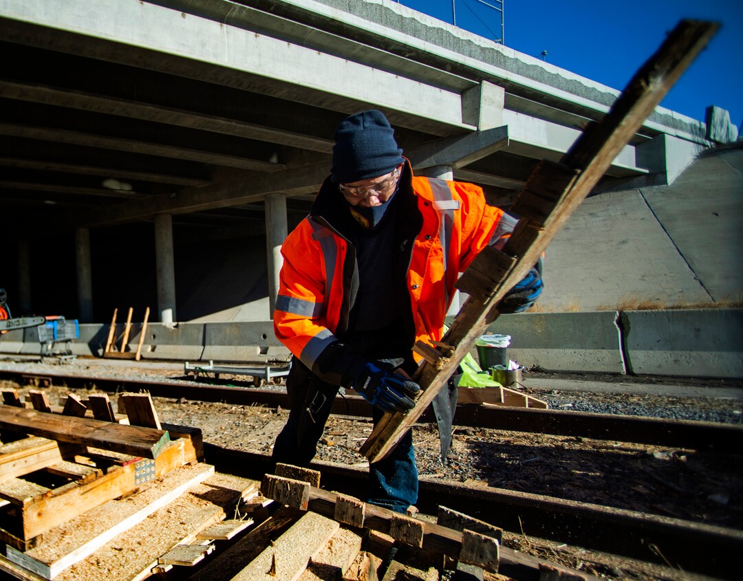 (Rick Egan | The Salt Lake Tribune) Wood manager, Michael Najera, (right) wears an orange reflective jacket as he chops up an old palette for firewood, at Camp Last Hope, on Tuesday, Jan. 5, 2021.