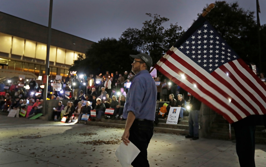 Steve Bird, of Greensboro, N.C., walks past a group of protesters during a rally outside the Guilford County Courthouse against President Trump's Attorney General choice that could jeopardize the special council's work in Greensboro, N.C., Thursday, Nov. 8, 2018. (AP Photo/Chuck Burton)