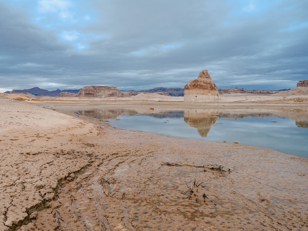 (Cody Cobb for The New York Times) Lone Rock reflected in muddy waters at Wahweap Bay in Lake Powell. On Wednesday, the Colorado River Basin states announced different proposals for how the river's water and its reservoirs, like Lake Powell, should be managed after 2026.