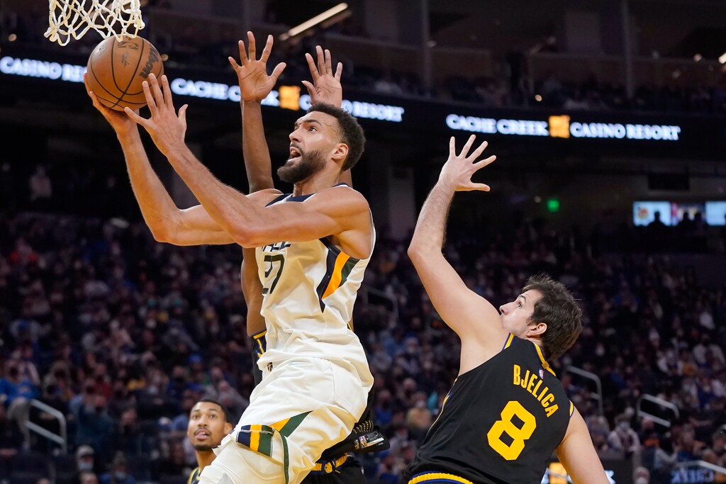 Utah Jazz center Rudy Gobert, left, shoots against Golden State Warriors forward Nemanja Bjelica (8) during the second half of an NBA basketball game in San Francisco, Sunday, Jan. 23, 2022. (AP Photo/Jeff Chiu)