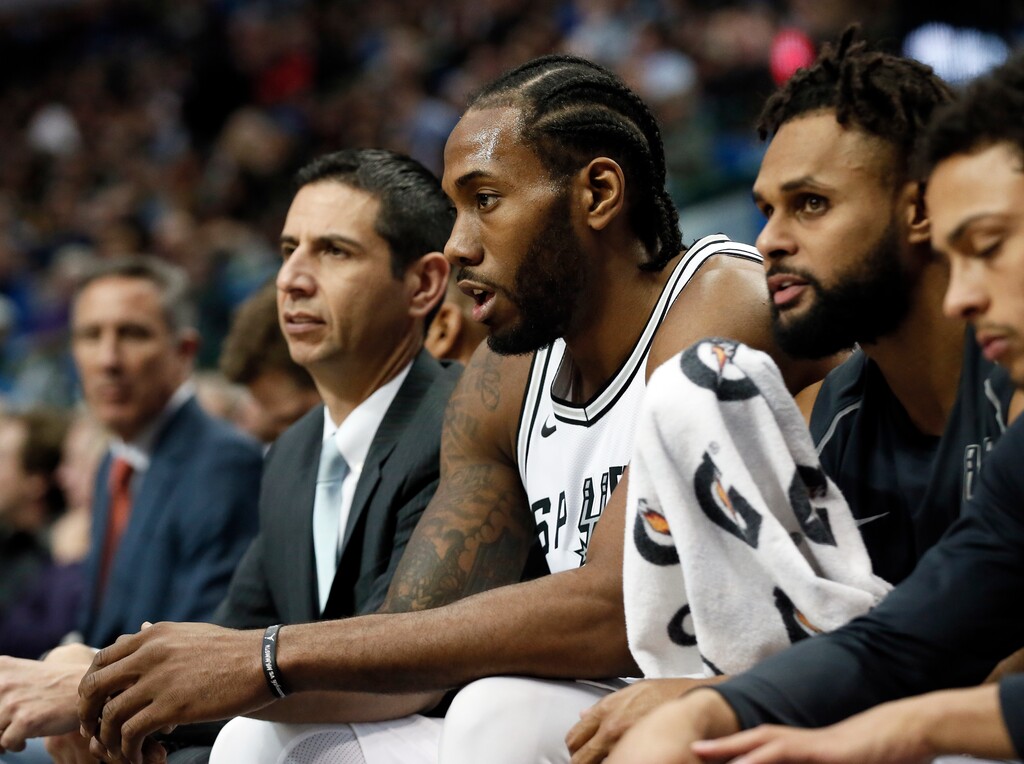 FILE - In this Tuesday, Dec. 12, 2017 file photo, San Antonio Spurs' Kawhi Leonard, center, sits on the bench after playing in the first half of an NBA basketball game against the Dallas Mavericks in Dallas. The San Antonio Spurs say Kawhi Leonard will be out indefinitely as he continues his recovery from a leg injury, Wednesday, Jan. 17, 2018. Leonard has played in just nine games after missing the beginning of the season because of right quadriceps tendinopathy. He also was sidelined briefly because of a shoulder injury. (AP Photo/Tony Gutierrez, File)