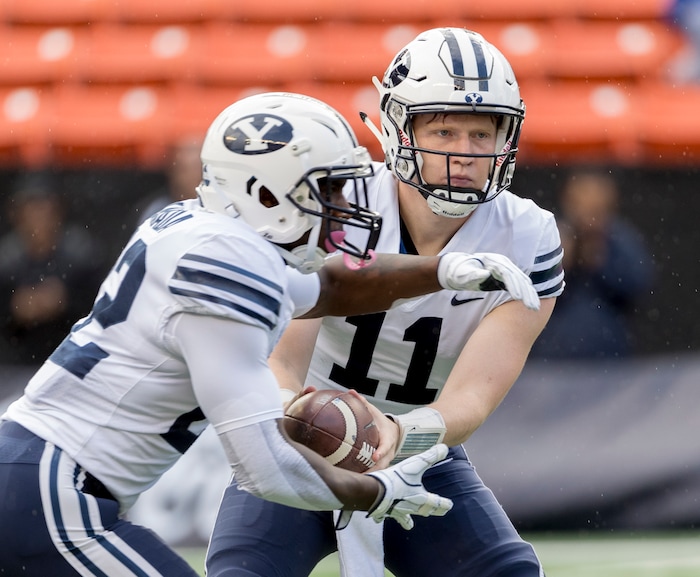 BYU quarterback Joe Critchlow (11) hands off the football to running back Squally Canada (22) in the first quarter of an NCAA college football game, Saturday, Nov. 25, 2017, in Honolulu. (AP Photo/Eugene Tanner)