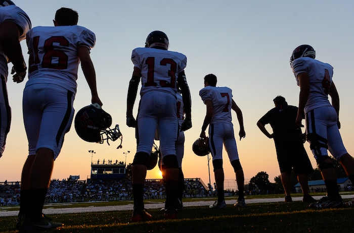 (Francisco Kjolseth | The Salt Lake Tribune)  The sun sets on a smoky sky as Hurricane players wait their turn to battle Skyline during the season opener at Skyline on Thursday, Aug. 20, 2015.