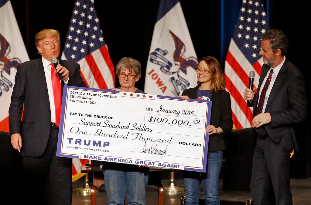 FILE - In this Jan. 31, 2016, file photo, Donald Trump, left, stages a check presentation with an enlarged copy of a $100,000 contribution from the Donald J. Trump Foundation to Support Siouxland Soldiers during a campaign event in Sioux City, Iowa. New York Attorney General Barbara Underwood filed a lawsuit Thursday, June 14, 2018, accusing Trump of illegally using his charitable foundation to pay legal settlements related to his golf clubs and to bolster his presidential campaign with foundation disbursements such as this one. (AP Photo/Patrick Semansky, File)