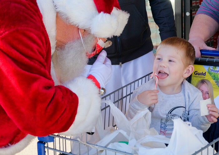 (Leah Hogsten  |  The Salt Lake Tribune)  Bronson Afoa, 2, was so excited to get a candy cane that he took a lick of the plastic wrapper while visiting Santa at Macey's grocery store on Thursday. The jolly fat man also greeted Macey's guests who scheduled a grocery pickup time, Dec. 24, 2020.