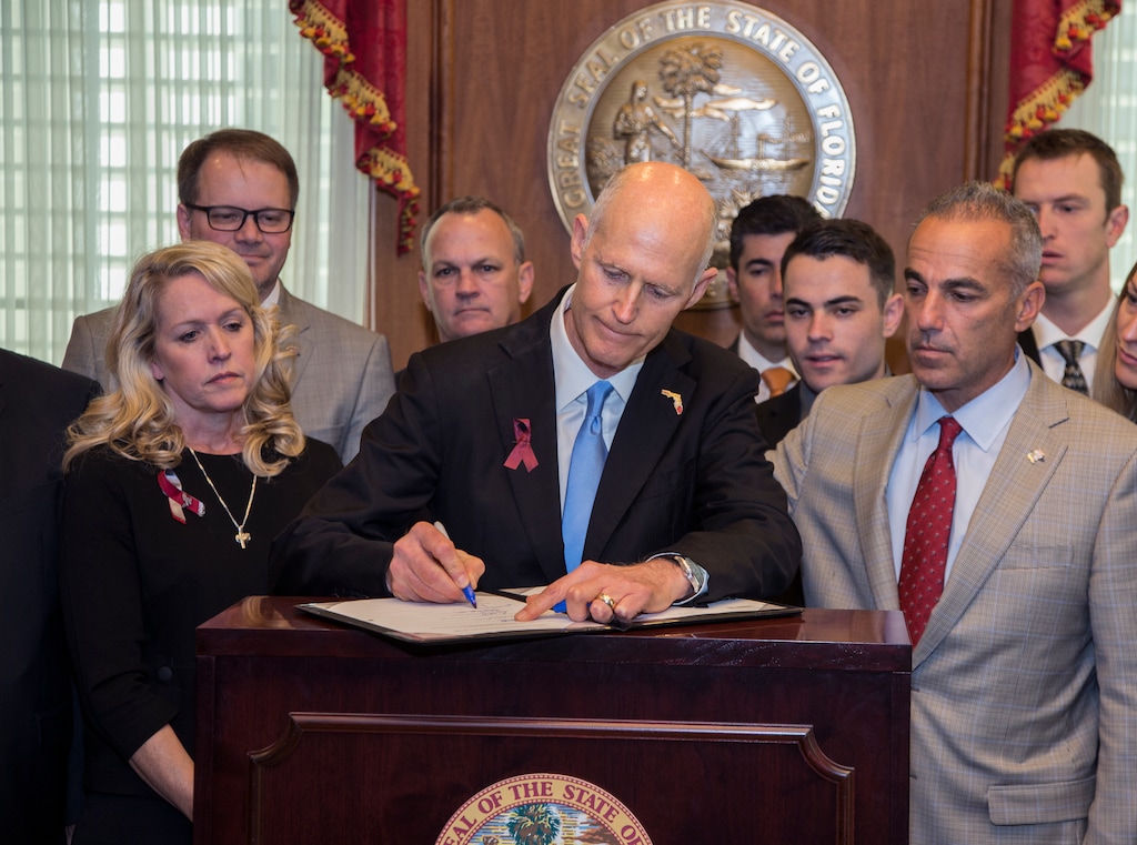 (Mark Wallheise | The Associated Press) Florida Gov. Rick Scott signs the Marjory Stoneman Douglas Public Safety Act in the governor's office at the Florida State Capitol in Tallahassee, Fla., Friday, March 9, 2018. Scott is flanked by victims' parents Gena Hoyer, left, Ryan Petty, second from left, Andrew Pollack, right, and his son Hunter Pollack, second from right.