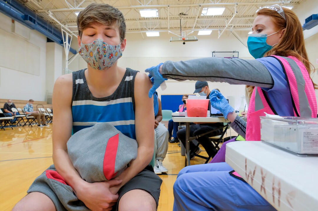 (Leah Hogsten | The Salt Lake Tribune) Parker Manning, 16, a student at Woods Cross High School, closes his eyes as he receives his first Pfizer vaccine from Pharmacist Shannon Stoker at a pop-up clinic by Nomi Health,  April 27, 2021. County and regional health districts are setting up vaccination clinics in high schools, to get the COVID-19 vaccine to 16 and 17-year-olds.