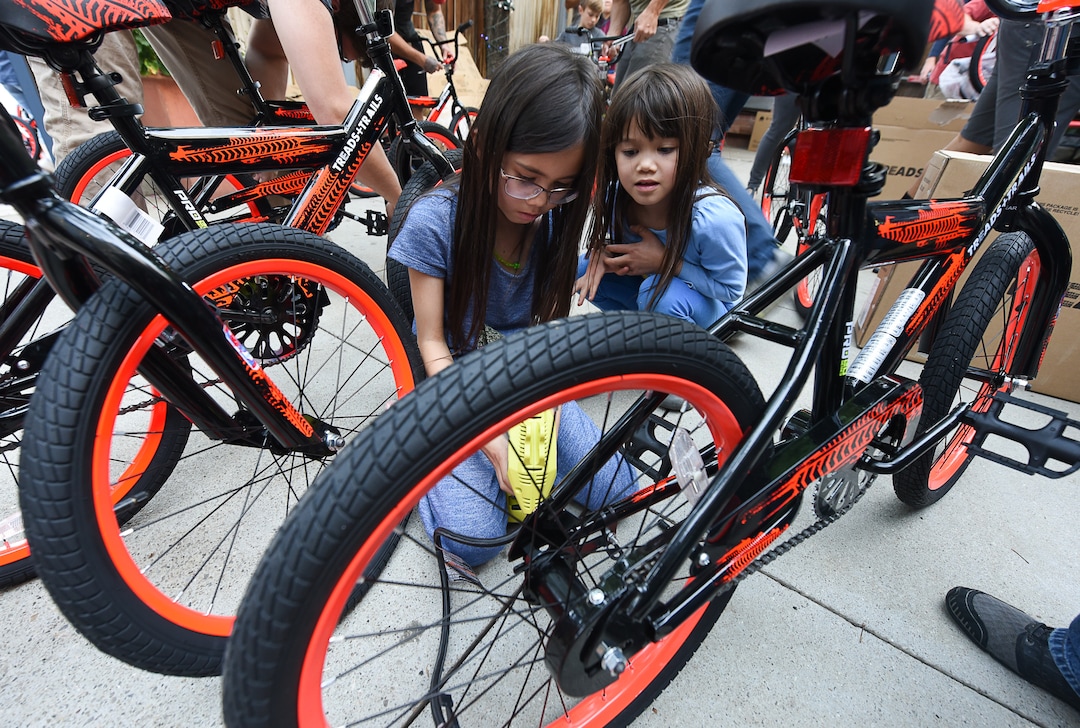 (Francisco Kjolseth  |  The Salt Lake Tribune)  WiVi Badger, 9, left, is joined by her sister Magnolia, 8, as they fill tires along with other volunteers and workers at Squatter's Pub Brewery to assemble 80 bicycles on Tuesday, May 29, 2018, at the brewery which will be given away to 1st and 2nd graders at Washington Elementary on Wednesday. Part of the program is backed by the Can'd Aid Foundation.