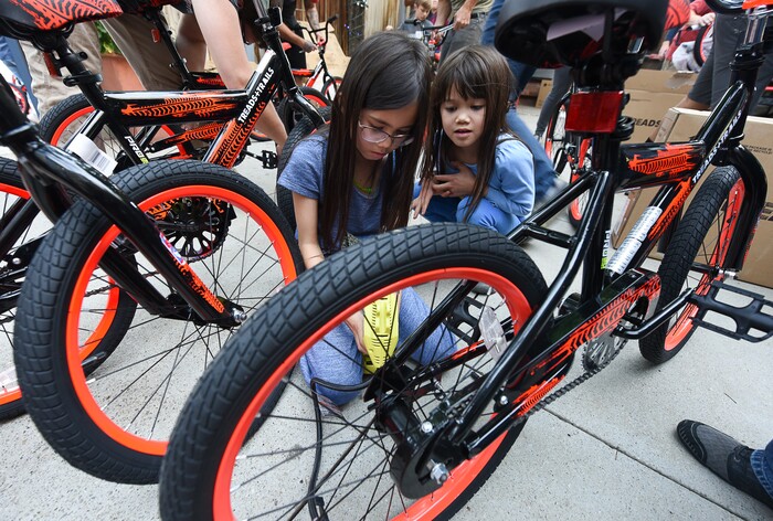 (Francisco Kjolseth  |  The Salt Lake Tribune)  WiVi Badger, 9, left, is joined by her sister Magnolia, 8, as they fill tires along with other volunteers and workers at Squatter's Pub Brewery to assemble 80 bicycles on Tuesday, May 29, 2018, at the brewery which will be given away to 1st and 2nd graders at Washington Elementary on Wednesday. Part of the program is backed by the Can'd Aid Foundation.