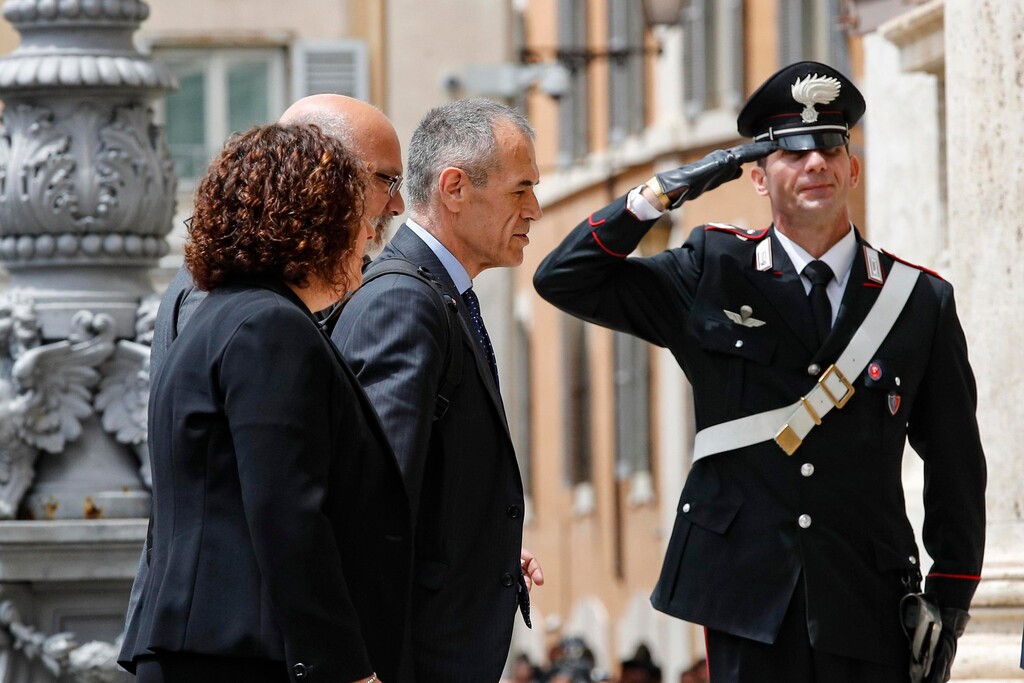 New premier-designate Carlo Cottarelli, center, is saluted by a Carabiniere paramilitary police officer as he arrives at the Lower Chamber palace, after meeting with Italian President Sergio Mattarella, at the Quirinale Presidential Palace, in Rome, Monday, May 28, 2018. Cottarelli was tapped on Monday to lead Italy to early elections, possibly as soon as after the summer, after populist political forces failed to convince the president their Cabinet picks wouldn’t destroy the faith of the markets and other investors.  (Giuseppe Lami/ANSA via AP)