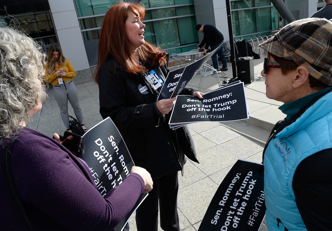 (Francisco Kjolseth  |  The Salt Lake Tribune) Laurie Woodward Garcia with MoveOn, hands out signs as a coalition of Republicans, Democrats and independents asking for a fair impeachment trial in the Senate gather for a news conference in front of Sen. Mitt Romney's office at the Wallace F. Bennett Federal building in Salt Lake City on Thursday, Jan. 16, 2020.