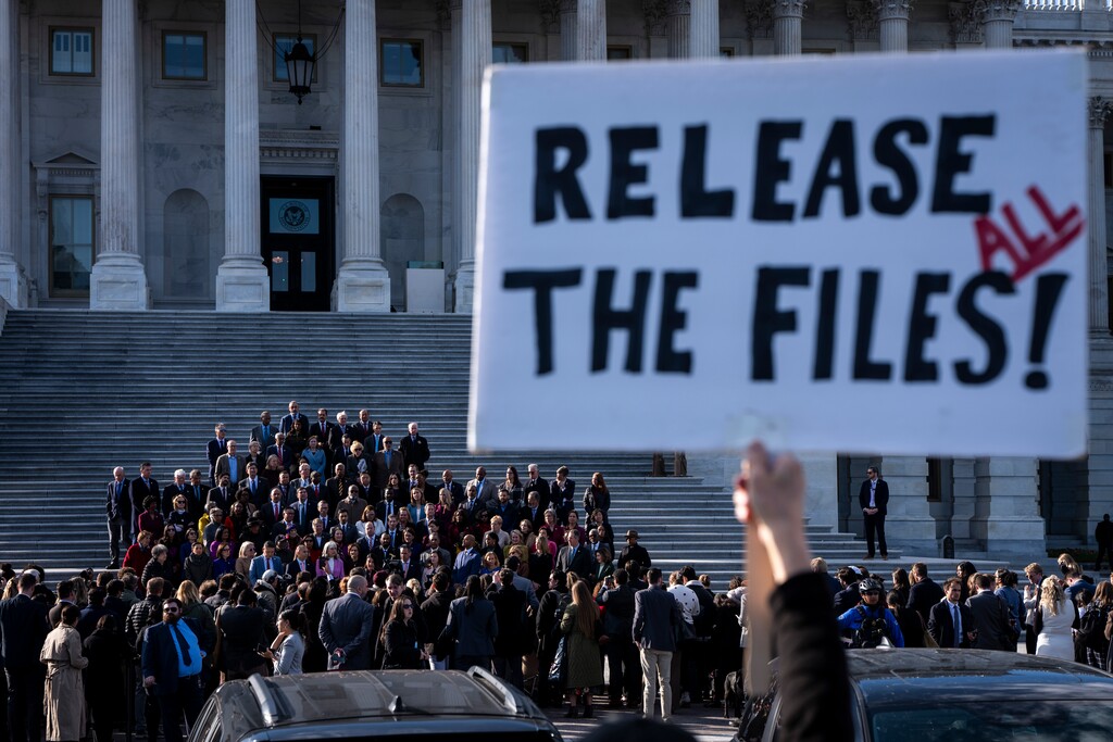 (Haiyun Jiang | The New York Times) A demonstrator holds a sign calling for the release of the Epstein files as House Democrats hold a news conference on the Capitol steps in Washington, on Wednesday, Nov. 12, 2025. House Republicans on Wednesday released 23,000 pages of documents from the estate of Jeffrey Epstein after months of delays.