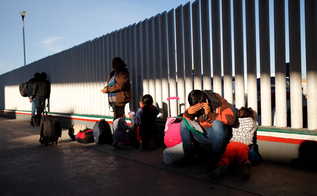 A migrant sits with his children as they wait to hear if their number is called to apply for asylum in the United States, at the border, Friday, Jan. 25, 2019, in Tijuana, Mexico. The Trump administration on Friday will start forcing some asylum seekers to wait in Mexico while their cases wind through U.S. courts, an official said, launching what could become one of the more significant changes to the immigration system in years. (AP Photo/Gregory Bull)