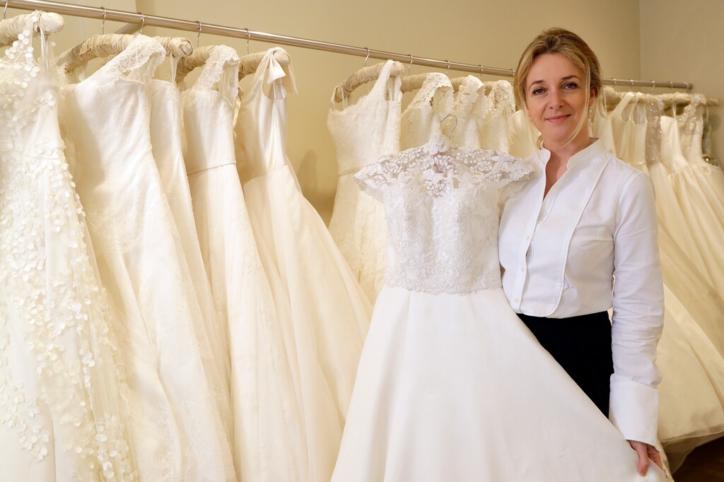 In this photo taken on Wednesday, April 18, 2018, Bridal designer Phillipa Lepley stands with a display of wedding dresses in her shop in London. With less than a month to go until she marries Prince Harry at Windsor Castle on May 19, Meghan Markle most likely has already chosen her wedding dress - though what it looks like is expected to remain a top secret until the last minute. A top-quality bespoke dress typically starts with a consultation to explore what styles fit the bride, followed by precise measurements and several initial fittings done in a mock-up fabric, according to leading London bridal designer Phillipa Lepley. “For a really exclusive dress it could take 60 hours plus (of labor), it depends on the embroidery. If it’s embroidered all over we’re talking hundreds of hours. The sky’s the limit,” Lepley said. “It really is very old-fashioned and all done by hand. It’s unbelievable how many hours things take." (AP Photo/Kirsty Wigglesworth)