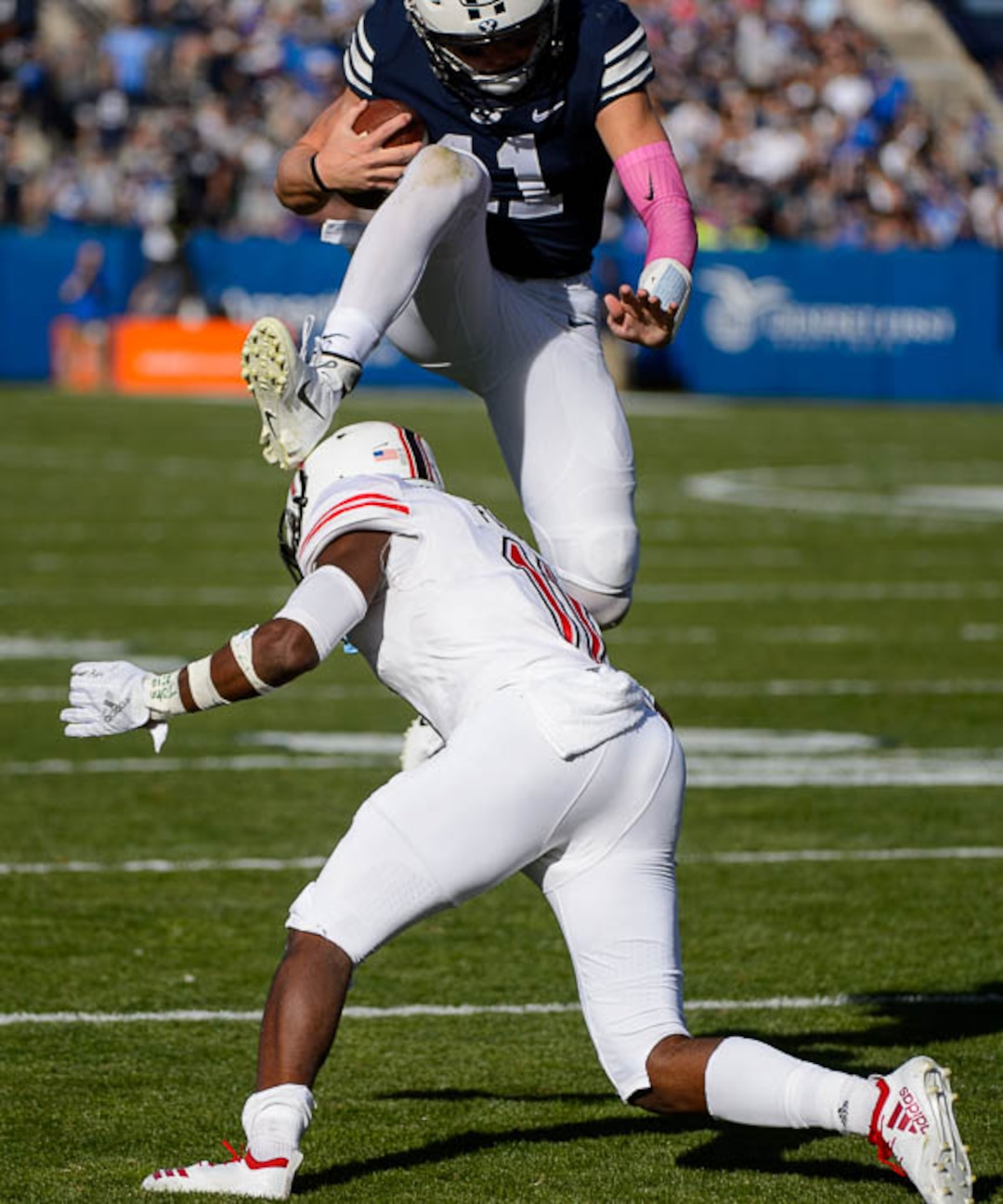 (Trent Nelson | The Salt Lake Tribune)  Brigham Young Cougars quarterback Zach Wilson (11) leaps over Northern Illinois Huskies safety Trayshon Foster (11) as BYU hosts Northern Illinois, NCAA football in Provo, Saturday Oct. 27, 2018.