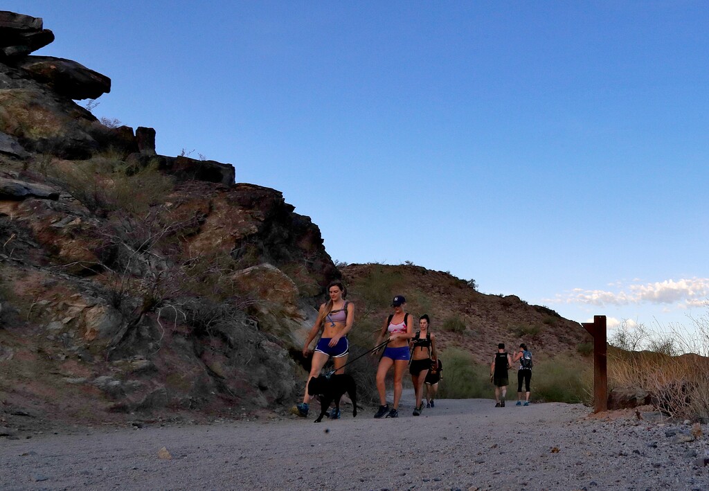 In this Tuesday, July 24, 2018 photo, hikers beat the heat on the trails at first light in Phoenix as temperatures exceed 95 degrees before sunrise. Phoenix on Tuesday recorded a sweltering 116 degrees (46 Celsius), tying the previous record set for the day in 2014. Officials in Phoenix and other cities are tackling urban warming caused by vast amounts of heat-retaining asphalt and concrete and too little trees. (AP Photo/Matt York)