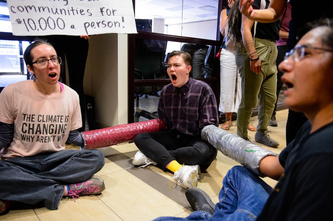 (Trent Nelson  |  The Salt Lake Tribune) Protesters locked together, occupying the Chamber of Commerce office in Salt Lake City on Tuesday, July 9, 2019. Dozens of people showed up to protest the proposed Inland Port and ended up clashing with police, resulting in temporary street closures and arrests.