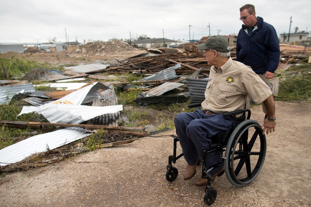 FILE - In this Aug. 28, 2017 file photo, Texas Gov. Greg Abbott surveys damage on Pearl Street in Rockport, Texas, during a tour of damage from Hurricane Harvey.  For US governors, including those taking office in early 2019, fires, floods and other climate-related emergencies could become top policy concerns. Texas has sought $12 billion from the federal government for a 60-mile coastal “spine” of concrete seawalls, floating gates and steel levees as a defense against future hurricanes and higher tides expected from climate change. (Courtney Sacco/Corpus Christi Caller-Times via AP, File)