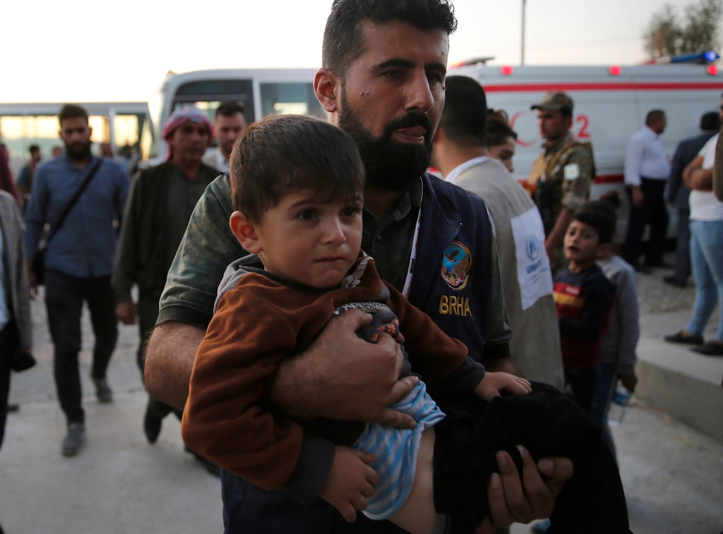 (Hussein Malla | AP) An Iraqi Kurdish humanitarian worker carries a Syrian boy, who is newly displaced with his family by the Turkish military operation in northeastern Syria, at the Bardarash camp, north of Mosul, Iraq, Wednesday, Oct. 16, 2019. The camp used to host Iraqis displaced from Mosul during the fight against the Islamic State group and was closed two years ago. The U.N. says more around 160,000 Syrians have been displaced since the Turkish operation started last week, most of them internally in Syria.