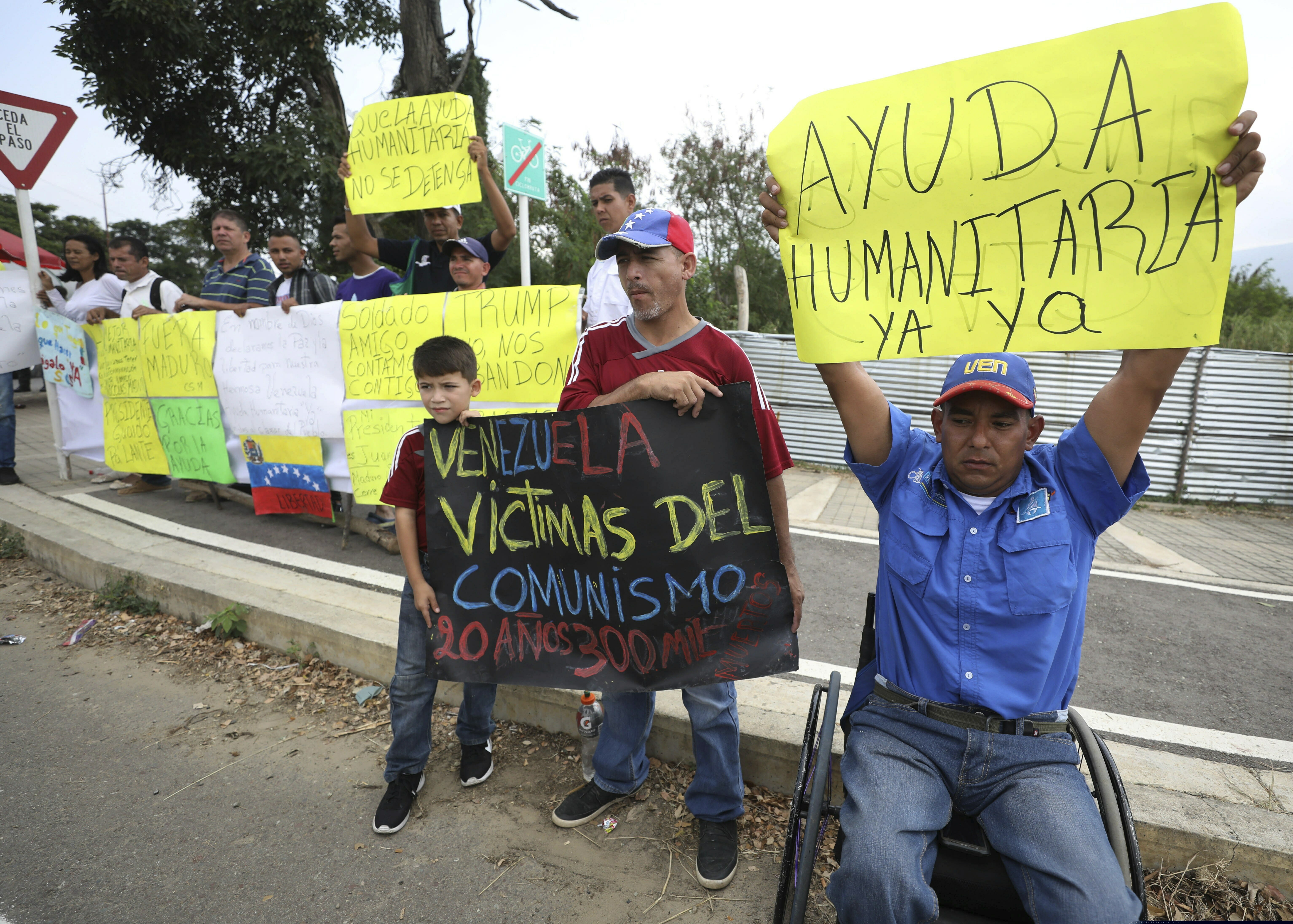 (Fernando Vergara | The Associated Press) Demonstrators hold signs in support of the country's self-proclaimed president Juan Guaido and and for foreign humanitarian aid, next to the Tienditas International Bridge, near Cucuta, Colombia, Friday, Feb. 8, 2019. Trucks carrying U.S. humanitarian aid destined for Venezuela arrived Thursday at the Colombian border, where opposition leaders vowed to bring them into their troubled nation despite objections from embattled President Nicolas Maduro.