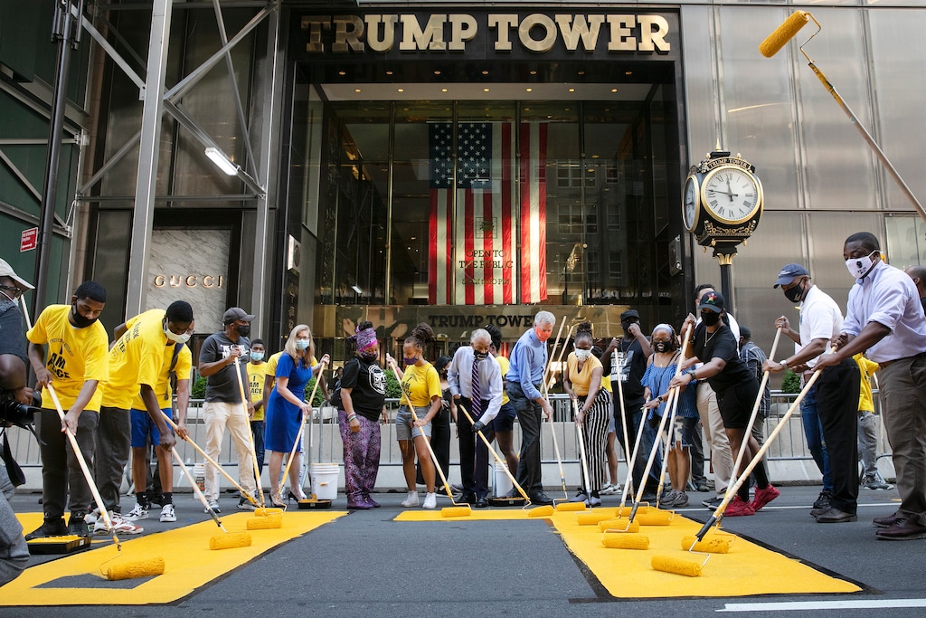 New York Mayor Bill de Blasio, wearing orange mask, participates in painting Black Lives Matter on Fifth Avenue in front of Trump Tower, Thursday, July 9, 2020, in New York. (AP Photo/Mark Lennihan)