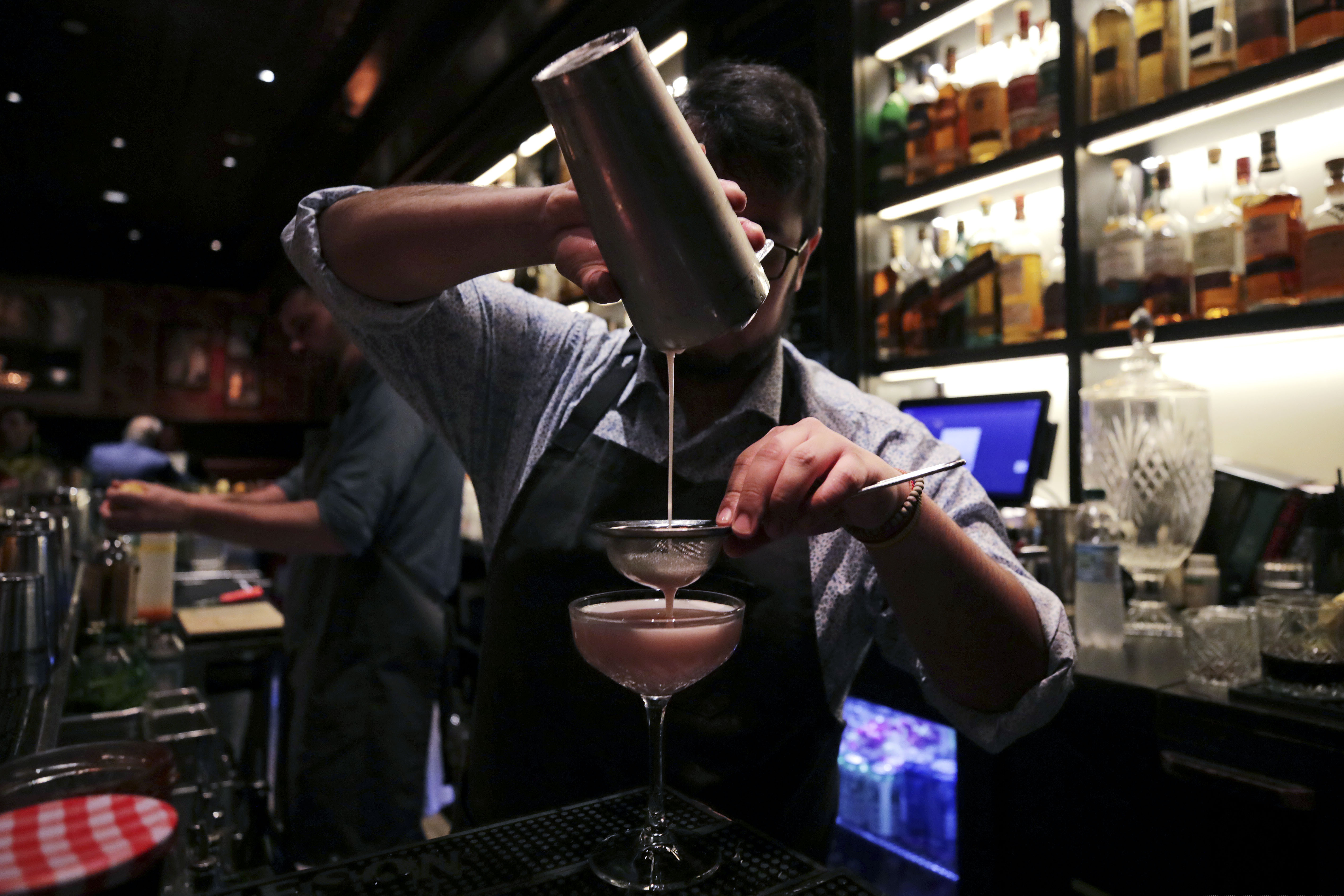 In this Dec. 10, 2019, photo mixologist Julian Bernal crafts a cocktail at Wink & Nod, basement-dwelling, speakeasy-like bar, in Boston. Americans are consuming more alcohol per capita now than in the time leading up to Prohibition, when alcohol opponents successfully made the case that excessive drinking was ruining family life. (AP Photo/Charles Krupa)