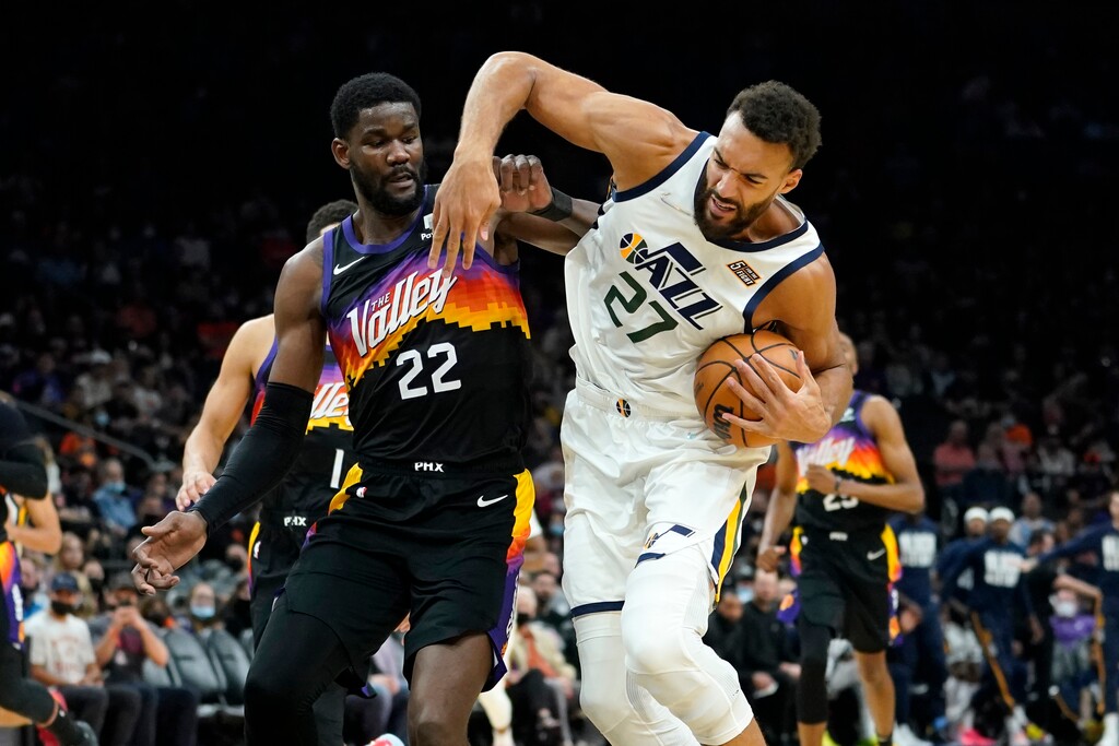 Utah Jazz center Rudy Gobert (27) drives on Phoenix Suns center Deandre Ayton (22) during the first half of an NBA basketball game, Sunday, Feb. 27, 2022, in Phoenix. (AP Photo/Matt York)