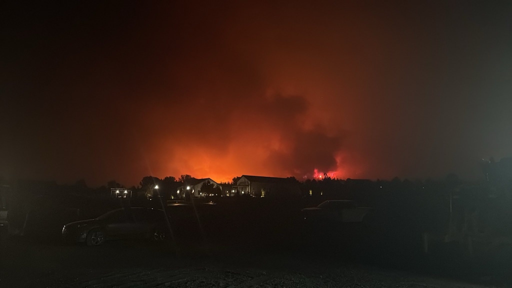 A dark nighttime scene of Pine Valley, with a red, smokey sky rising behind homes.