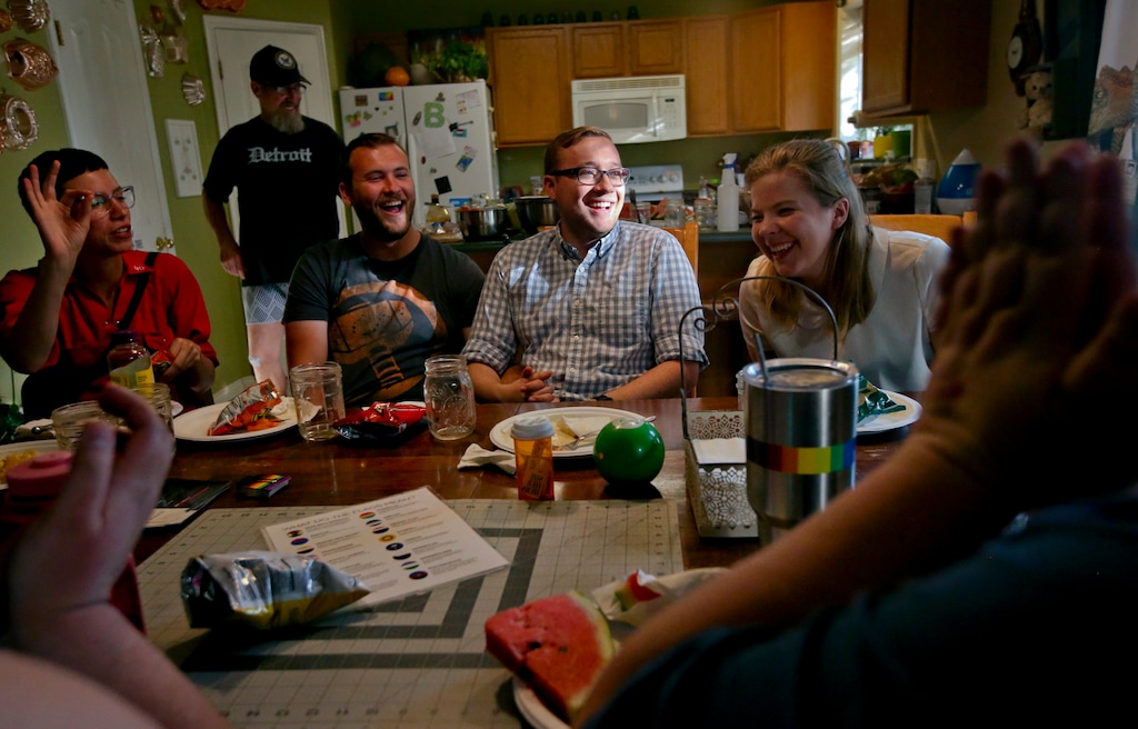 Taylor Steed, center, of Orem, and Nick Maughan, center left, of Provo, laugh at a joke as they and other community members eat during a QueerMeals gathering Saturday, July 7, 2018, at Jeff and Jerilyn Pool's home in Provo, Utah. Though the name of the nonprofit the Pools run out of their home implies that the organization’s mission is all about food, QueerMeals has a larger, overarching purpose beyond just keeping people in Utah County’s LGBTQ community fed.  (Isaac Hale/The Daily Herald via AP)
