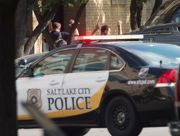 (Rick Egan  |  The Salt Lake Tribune)   Workers are escorted out of their building with there hands in the air, as police search for a suspect after he fired shots at a police officer on Rio Grande Street, Wednesday, Sept. 5, 2018.


