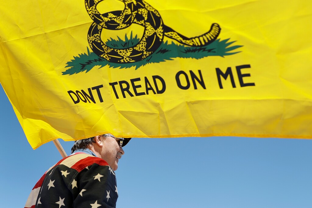 A man holds a flag as he attends a rally to protest stay-at-home orders put into place due to the COVID-19 outbreak Tuesday, April 21, 2020, outside the Missouri Capitol in Jefferson City, Mo. Several hundred gathered to protest the restrictions and urge the reopening of businesses closed in an effort to slow the spread of the coronavirus . (AP Photo/Jeff Roberson)
