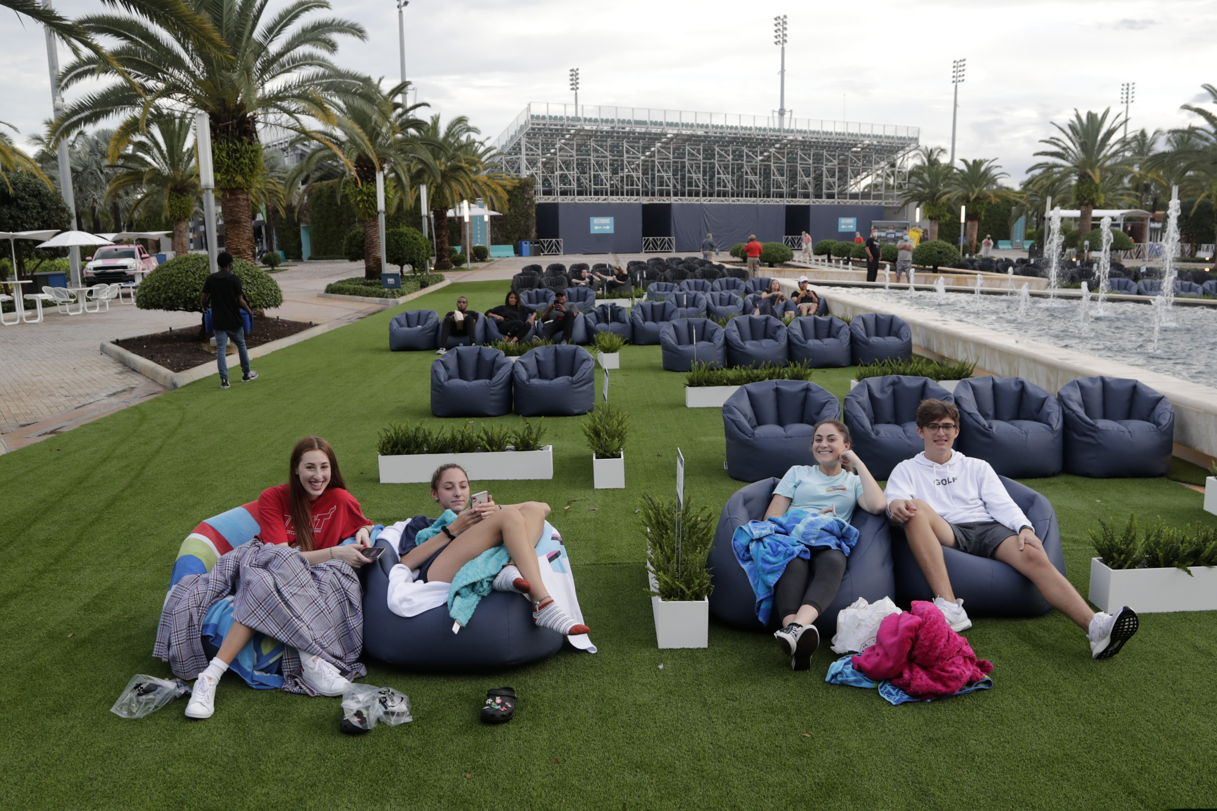 FILE - In this Thursday, June 18, 2020 file photo, people sit outdoors to watch a movie as part of a program offered by the Miami Dolphins at Hard Rock Stadium during the coronavirus pandemic in Miami Gardens, Fla. Elected officials such as Florida's governor have argued against reimposing restrictions, saying many of the newly infected are young and otherwise healthy. But younger people, too, face the possibility of severe infection and death. And authorities worry that older, more vulnerable people could be next. (AP Photo/Lynne Sladky)