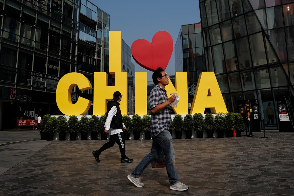 (Andy Wong | AP file photo) In this Sept. 29 photo, a man eats a snack while passing an "I love China" decoration at a popular shopping mall in Beijing. China is putting a positive face on an agreement to start dialing down a trade war that it blames the U.S. for starting. Chinese experts and news media said Saturday that the deal would reduce uncertainty for companies and lay the foundation for further talks.