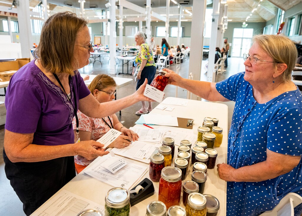 (Rick Egan | The Salt Lake Tribune)   Jonalee Kump and Heather Bailey, at left, assist Pam Carson, 77, as she enters her jams, fruits and pickles for the State Fair, in the Zion Building at the Utah State Fair Park, on Friday, Sept. 1, 2023.