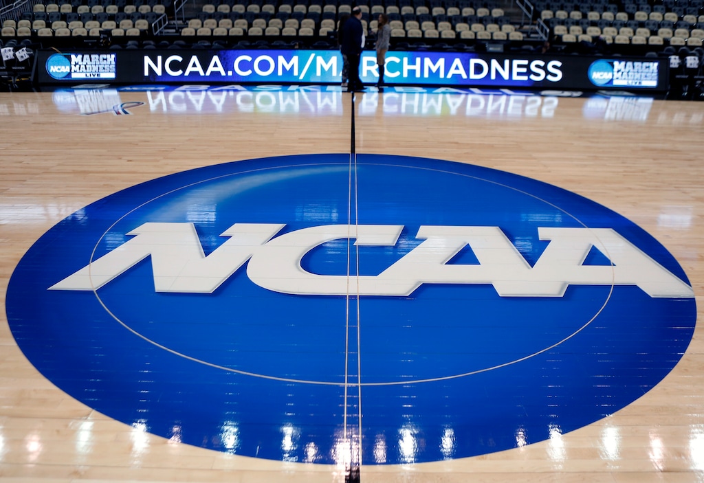 FILE - In this March 18, 2015, file photo, the NCAA logo is displayed at center court as work continues at The Consol Energy Center in Pittsburgh, for the NCAA college basketball tournament. The NCAA took a significant step toward allowing all Division I athletes to transfer one time without sitting out a season of competition. A plan to change the waiver process is expected to be presented to the Division I Council in April, 2020. If adopted, new criteria would go into effect for the 2020-21 academic year and be a boon for athletes in high-profile sports such as football and men's and women's basketball. (AP Photo/Keith Srakocic, File)