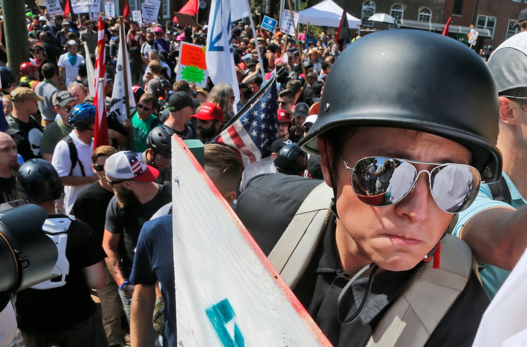 A white nationalist demonstrator with a helmet and shield walks into Lee Park in Charlottesville, Va., Saturday, Aug. 12, 2017.   Hundreds of people chanted, threw punches, hurled water bottles and unleashed chemical sprays on each other Saturday after violence erupted at a white nationalist rally in Virginia. At least one person was arrested.  (AP Photo/Steve Helber)