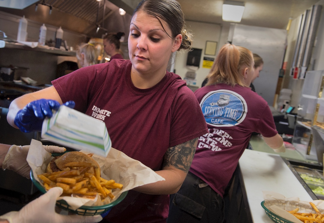 (Leah Hogsten  |  The Salt Lake Tribune) Chonsey Leslie dumps an order of fries onto a customer's order. Leslie and her fellow inmates are slammed with a line of customers every day from 11pm to 2pm closing time.  Every Monday through Friday, a half-dozen or so Level 4 inmates file out of the Olympus Facility at the Utah State Prison to cook, bake and serve the public at the Serving Time Caf. The operation is part of Utah Department of Corrections Industries (UCI) and is aimed at helping inmates return to society.