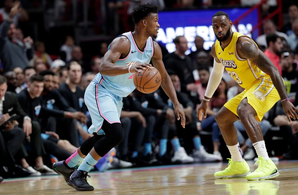 Miami Heat forward Jimmy Butler, left, drives to the basket as Los Angeles Lakers forward LeBron James (23) defends during the first half of an NBA basketball game, Friday, Dec. 13, 2019, in Miami. (AP Photo/Lynne Sladky)