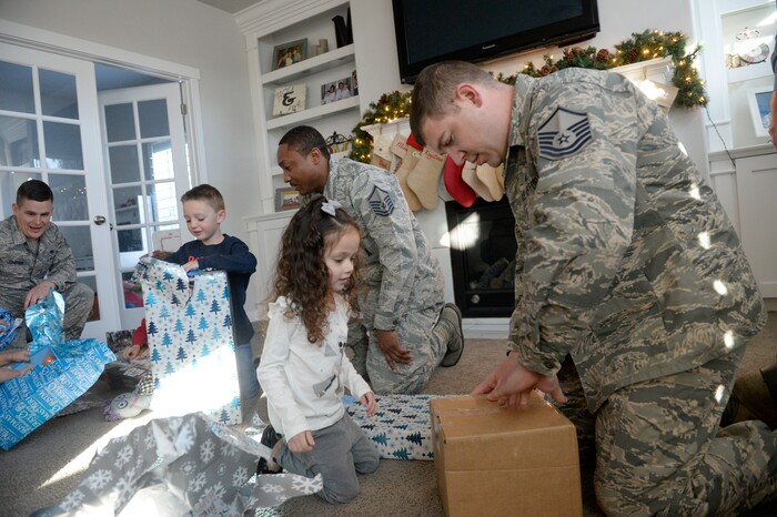 (Al Hartmann  |  The Salt Lake Tribune) 	Hill Air Force Base Airmen  S Sgt. Alec Johnson, left, M Sgy. Jeremiah Clark, and M Sgt. Greg Allen help adopted children Jaackson and Olivia McLain open presents Tuesday Dec. 19.   This year, Hill personel will deliver 948 gifts to 326 foster children along the Wasatch Front. 